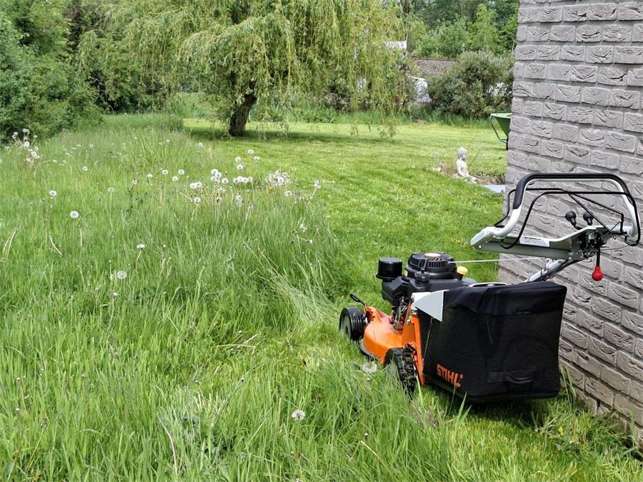 Benny zijn maaier en grasopvangbak op een half gemaaid veld