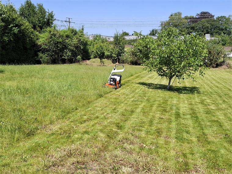Groot gemaaid veld met de maaier in de verte